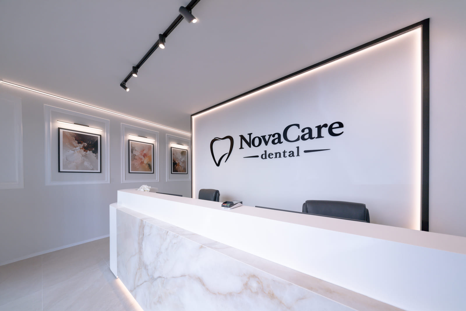 L’accueil de NovaCare Dental à Jette, avec son comptoir de pierre claire et le logo du cabinet.
